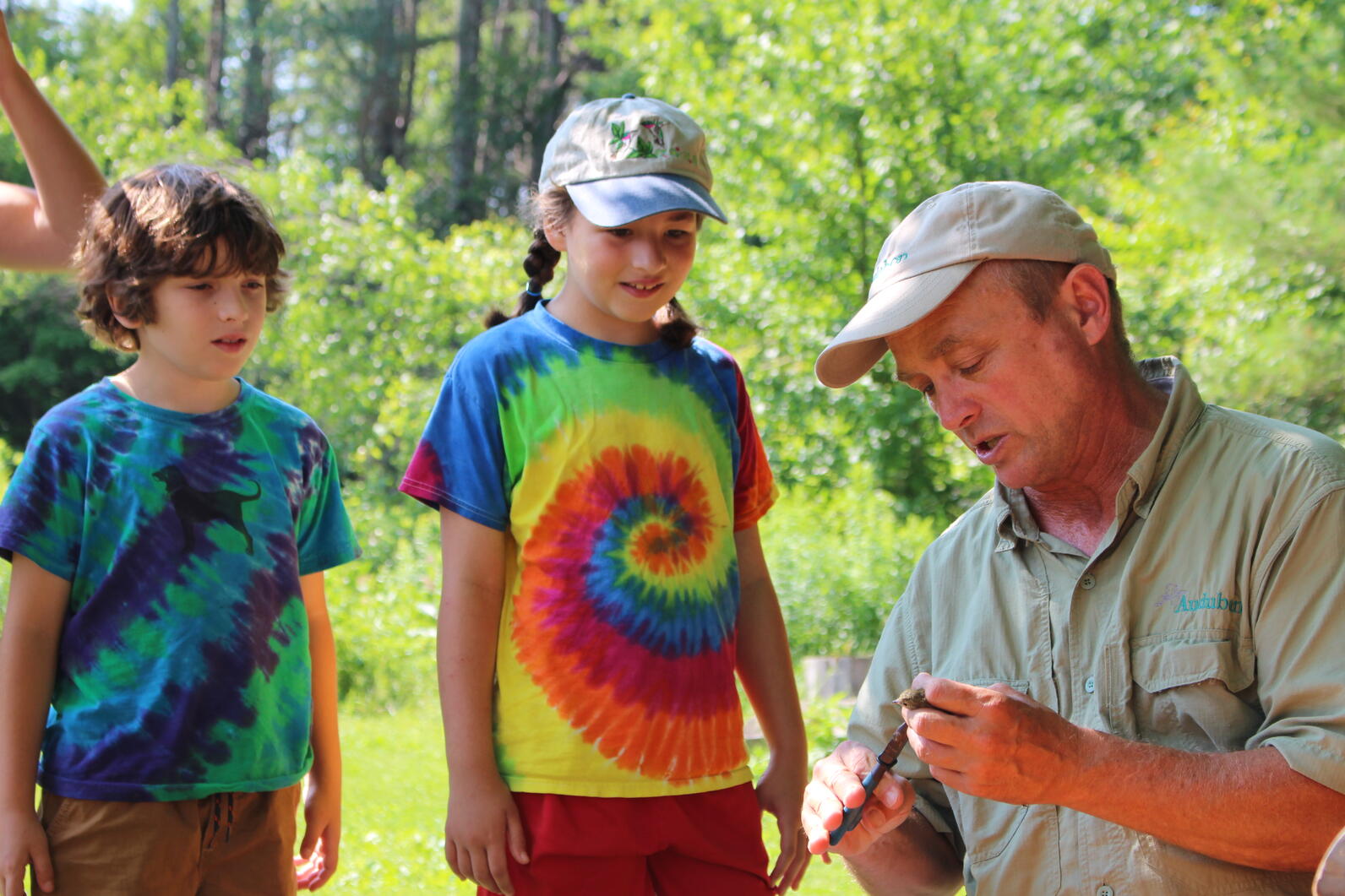 On the far left, Mark LaBarr holds a bird, as three children express awe to his right.