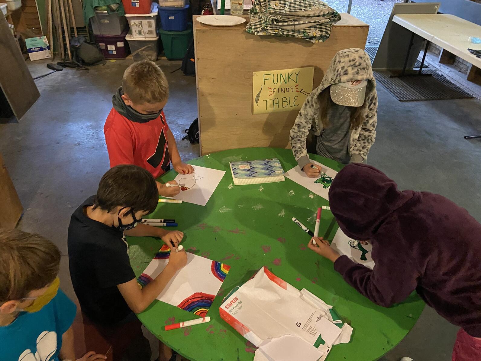 masked kids at camp, draw around a green table