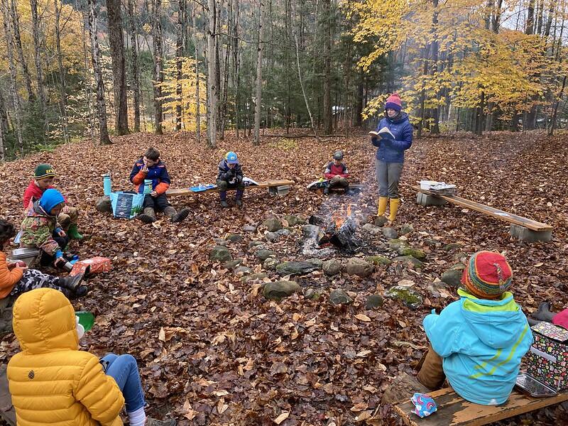 students eating lunch around a fire