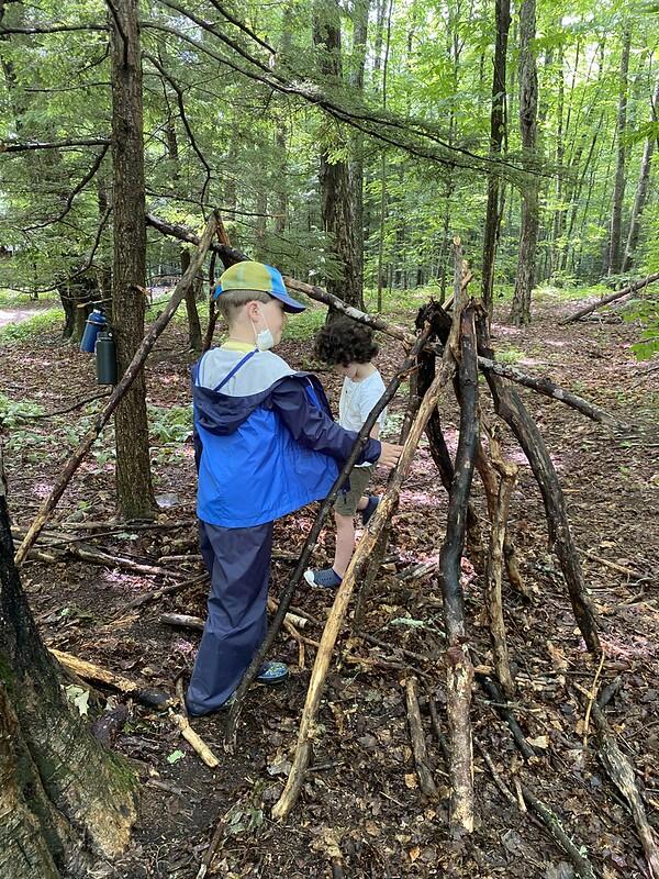 Students with sticks building shelter Students with sticks building shelter