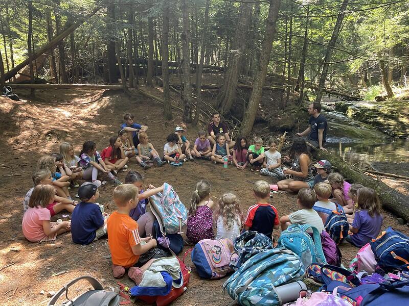 campers sitting in a circle at the brook
