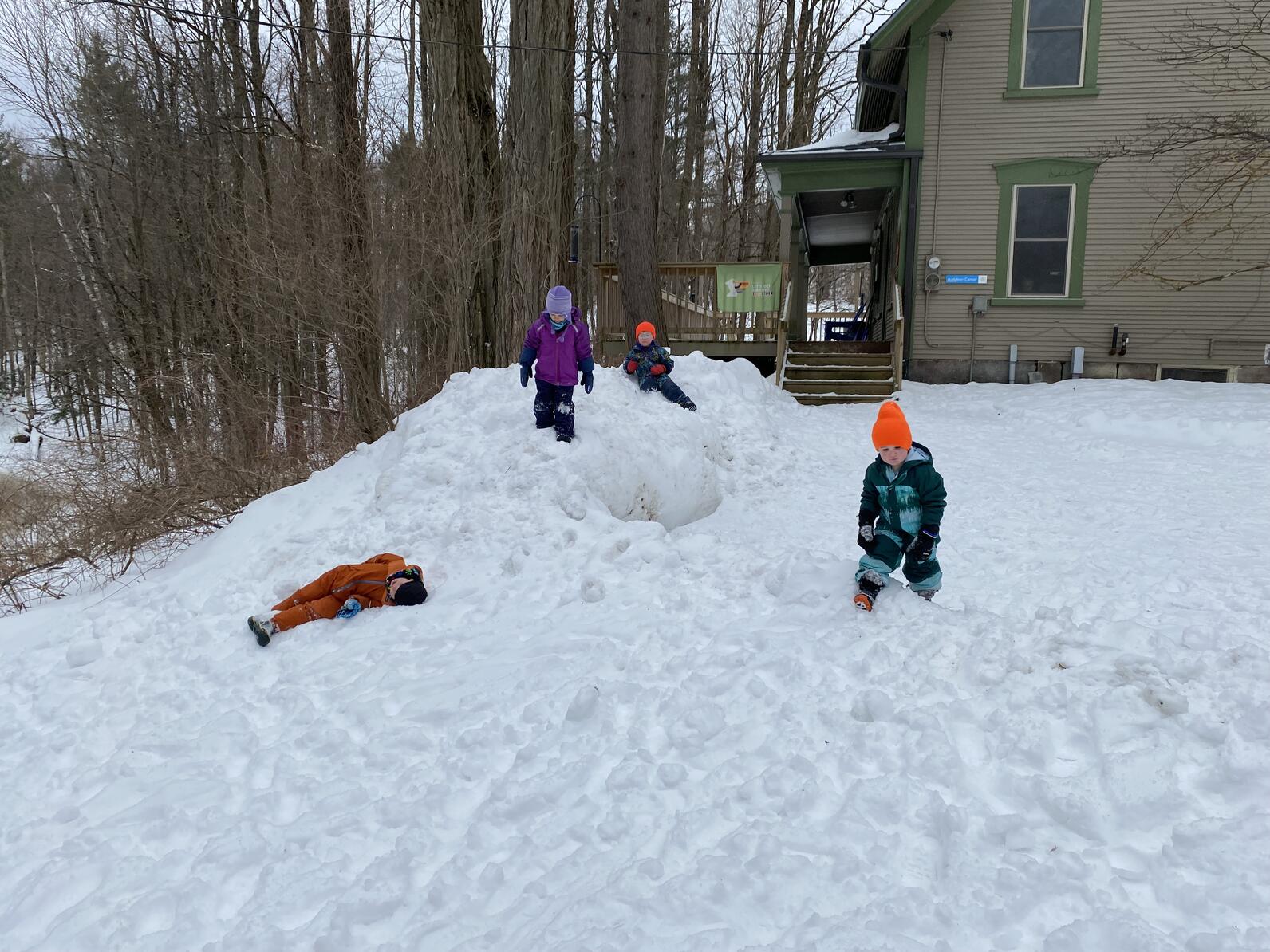 children play on a mound of snow