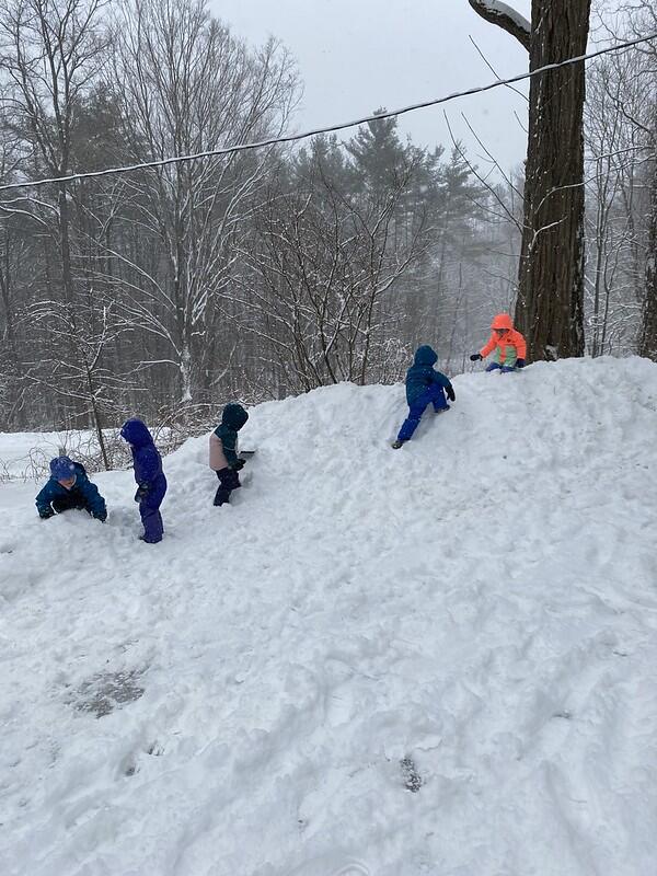 children climb up a snow bank