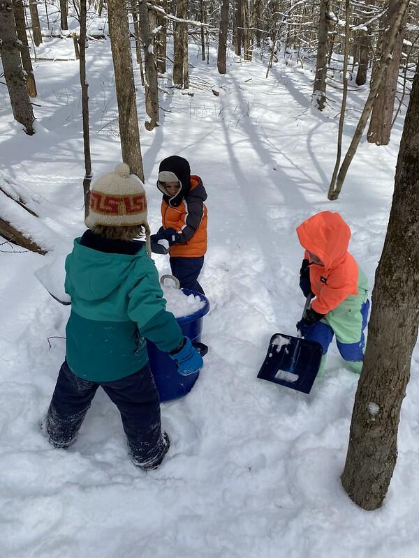 children fill a bucket with snow
