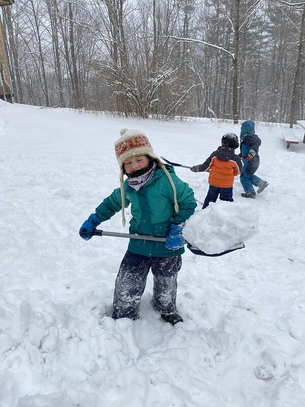 a child holds a shovel full of snow