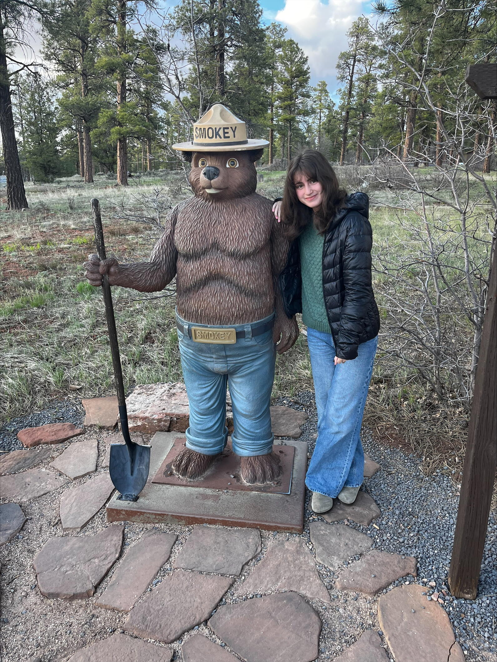 Lily smiles as she leans against a Smokey the Bear statue