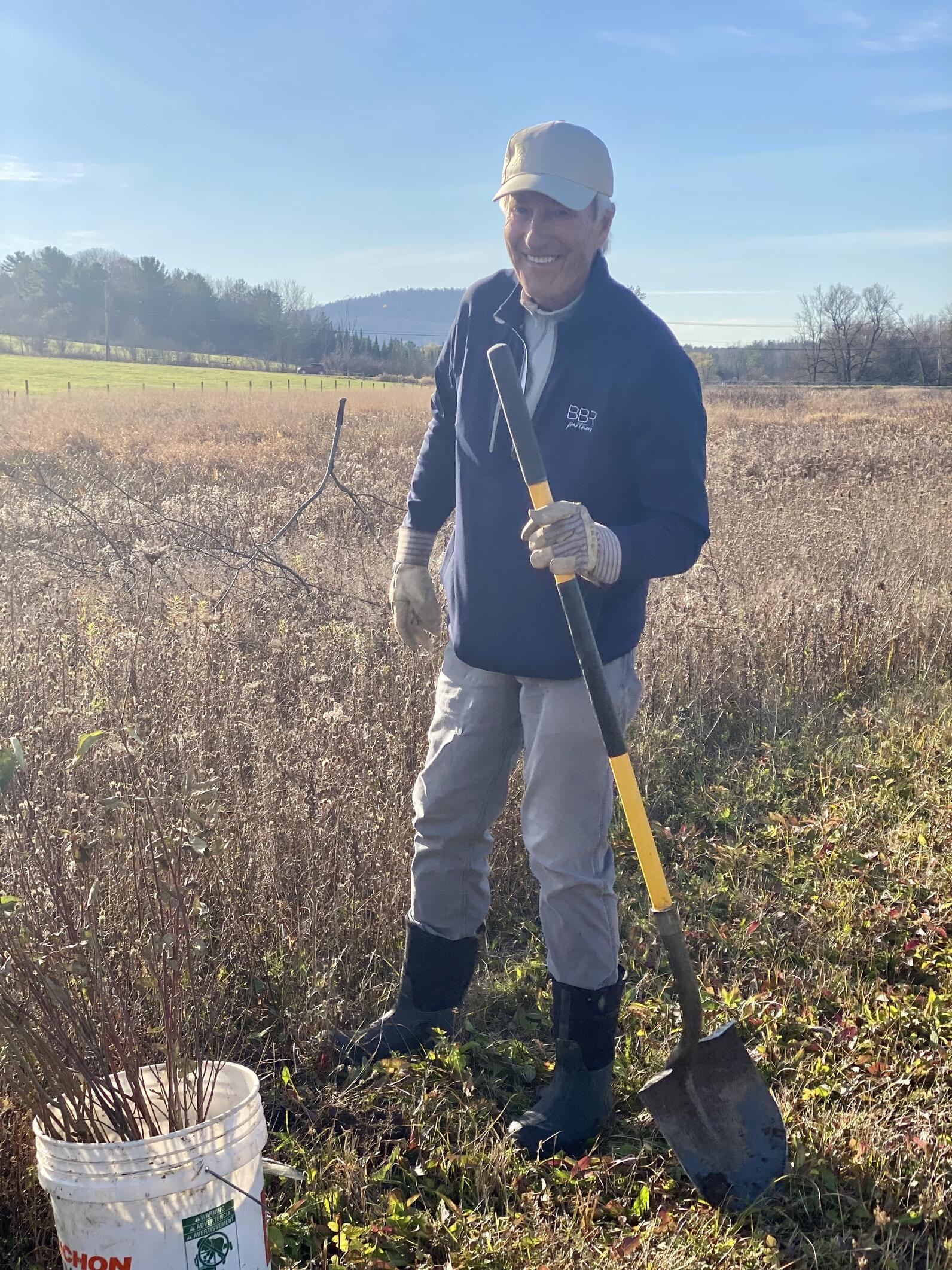 Man standing with a shovel preparing to plant a shrub