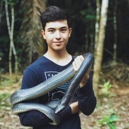 AmeriCorps member Truman holds a very large black and pale yellow Mussurana 