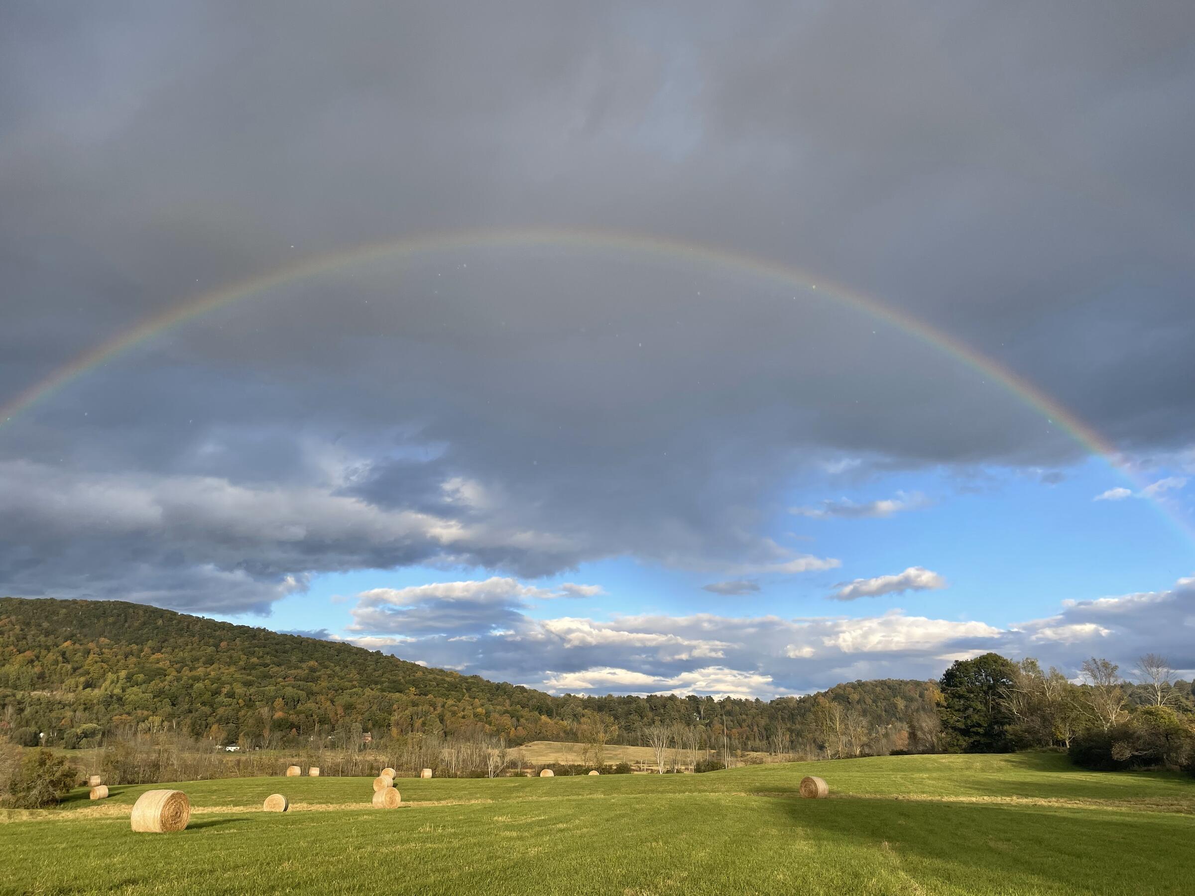 Field with rainbow and round hay bales